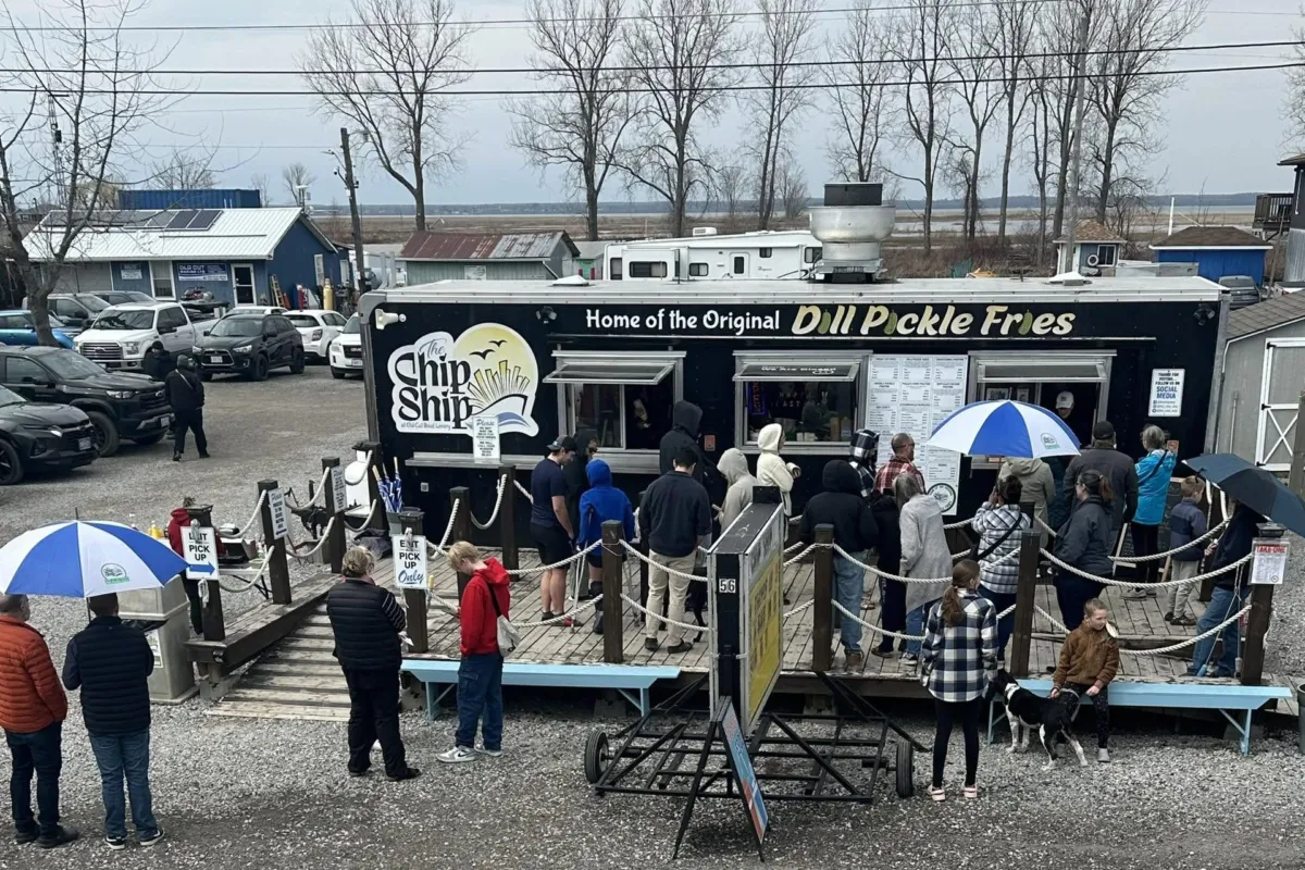Customers lined up on the deck at the Chip Ship food truck, Home of the Original Dill Pickle Fries, at Old Cut Boat Livery on…