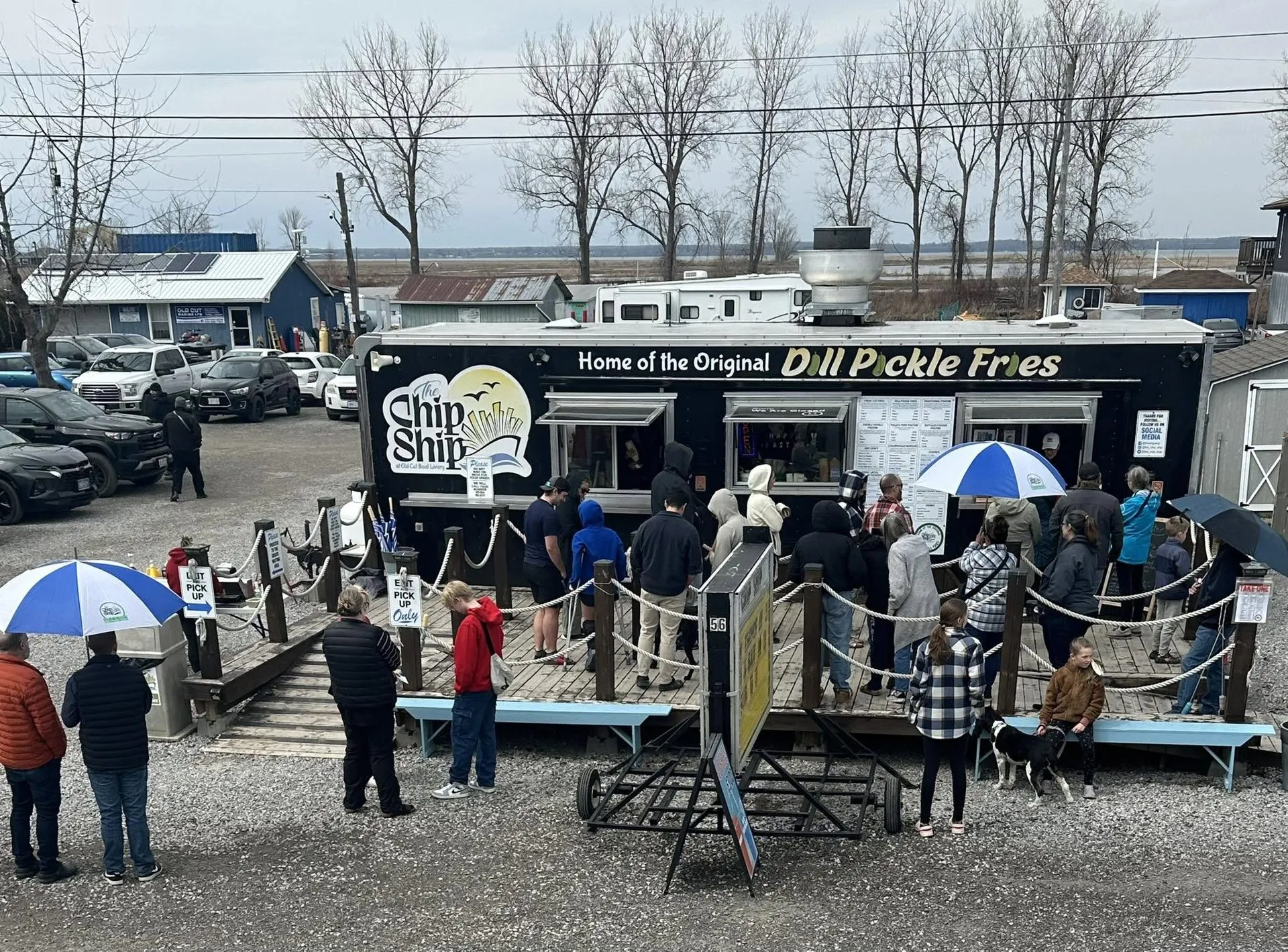 Customers lined up on the deck at the Chip Ship food truck, Home of the Original Dill Pickle Fries, at Old Cut Boat Livery on…